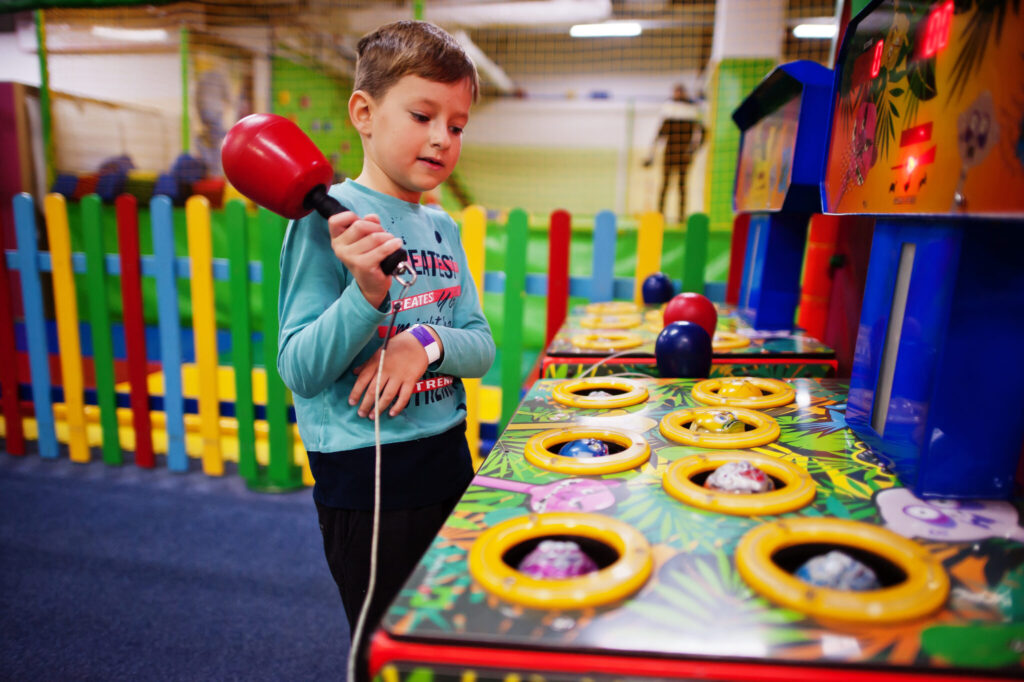 Boy play in hit the hamster game machine at indoor playground.