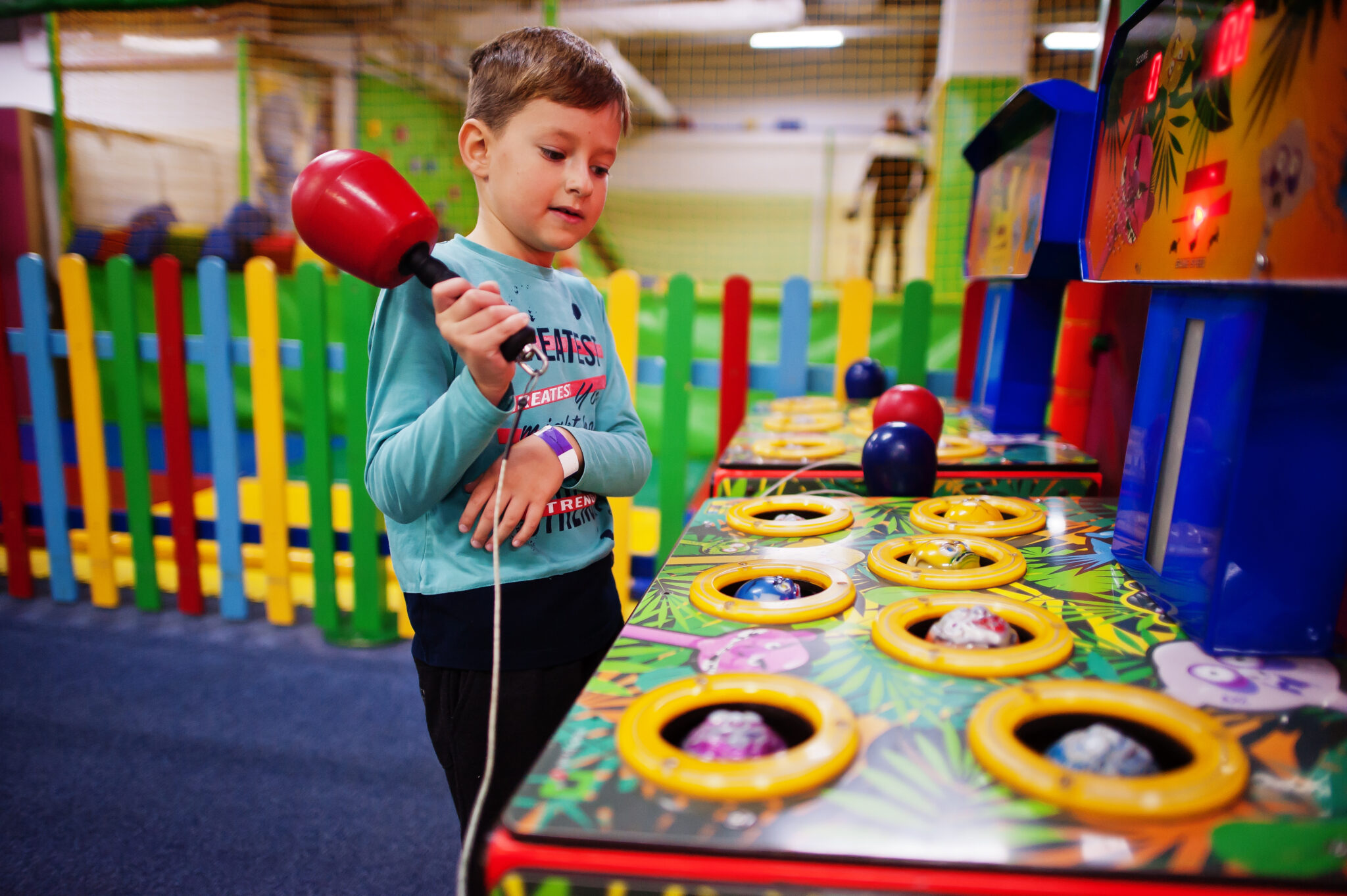 Boy play in hit the hamster game machine at indoor playground.